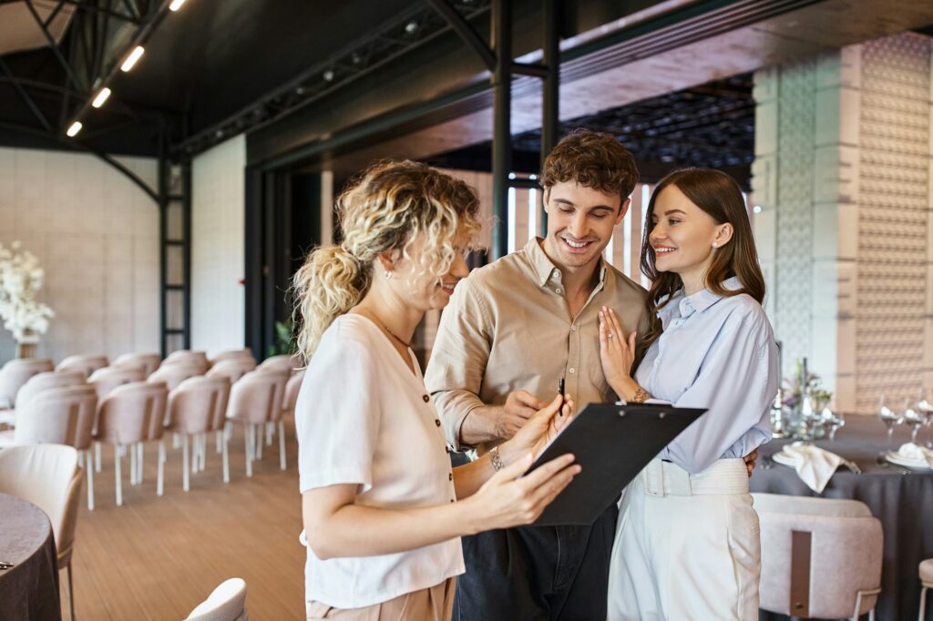 event coordinator giving clipboard with contract to happy couple in decorated wedding hall